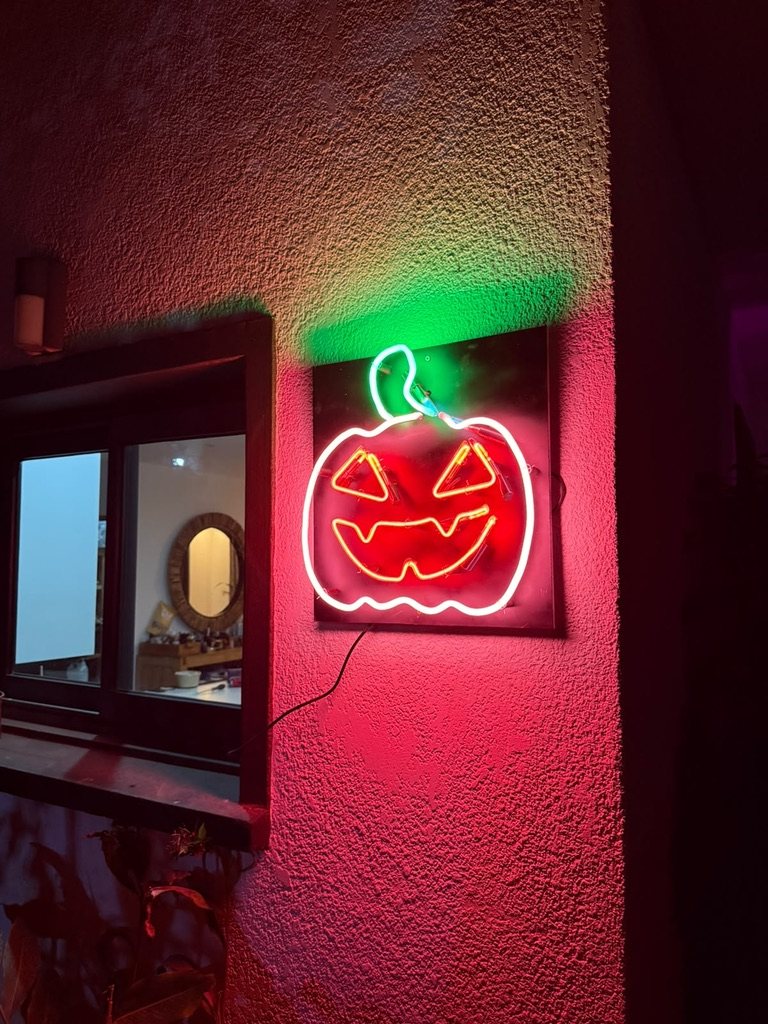 Citrouille d'Halloween en néon rouge, blanc et vert sur une façade