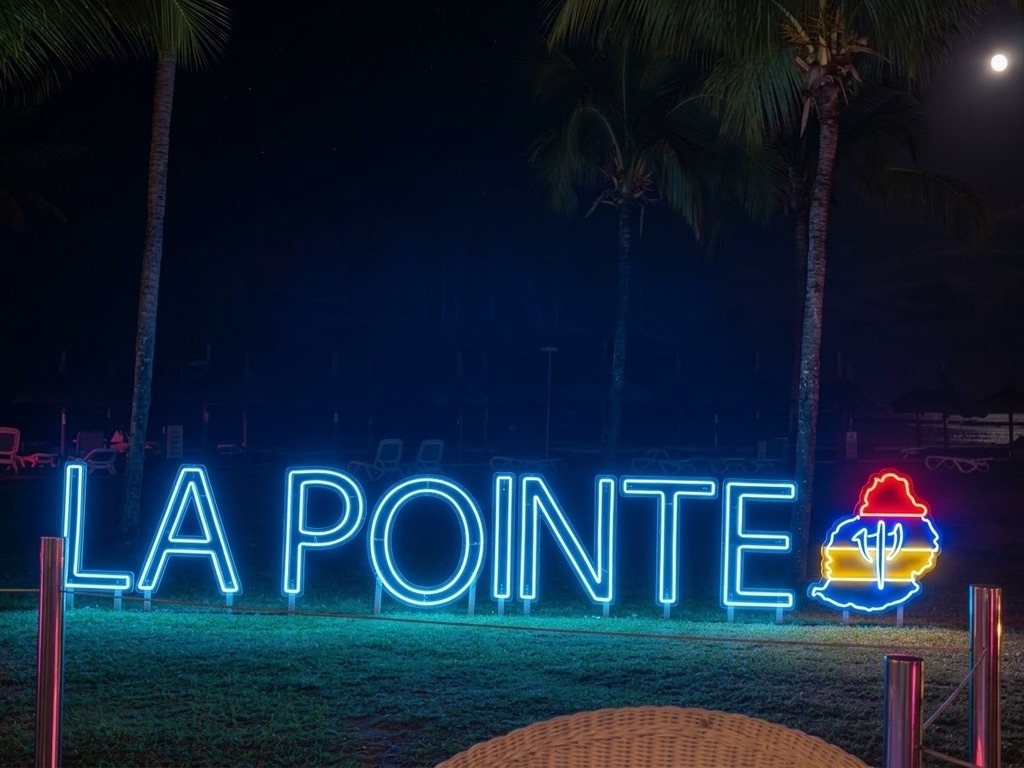 Enseigne néon bleue LA POINTE avec la carte de Maurice, la nuit sous les palmiers
