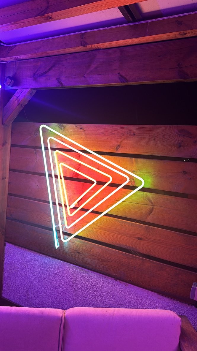 Triangles imbriqués en néon multicolore sur un mur en bois