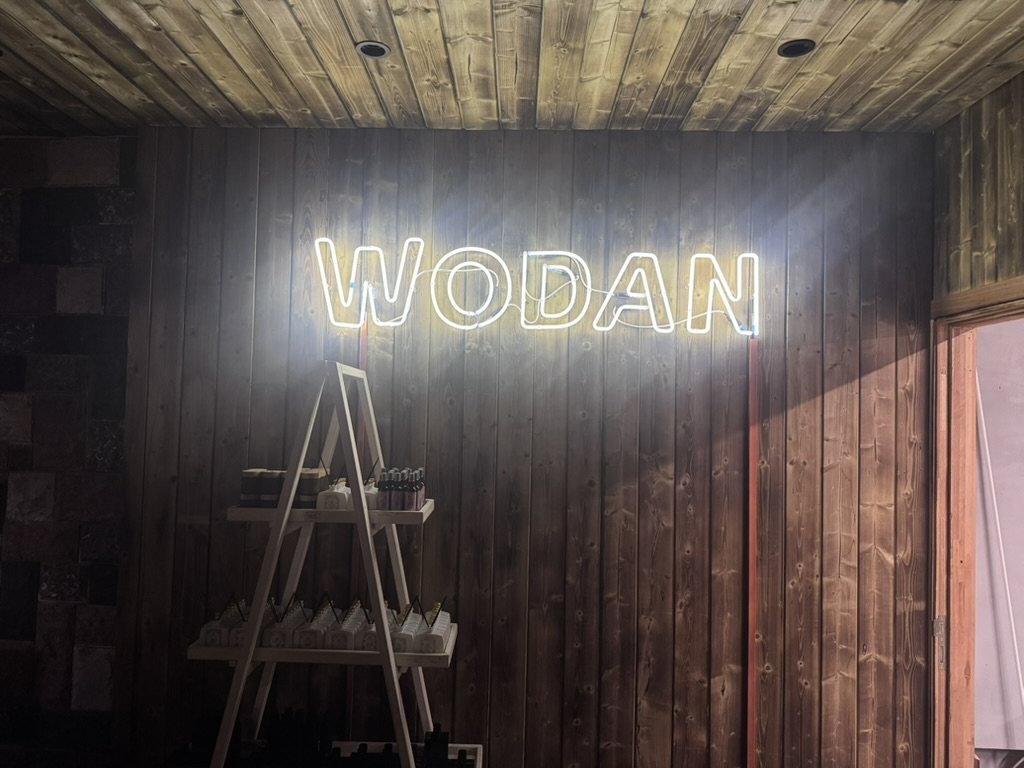 Enseigne WODAN en néon blanc chaud sur un mur en bois de boutique